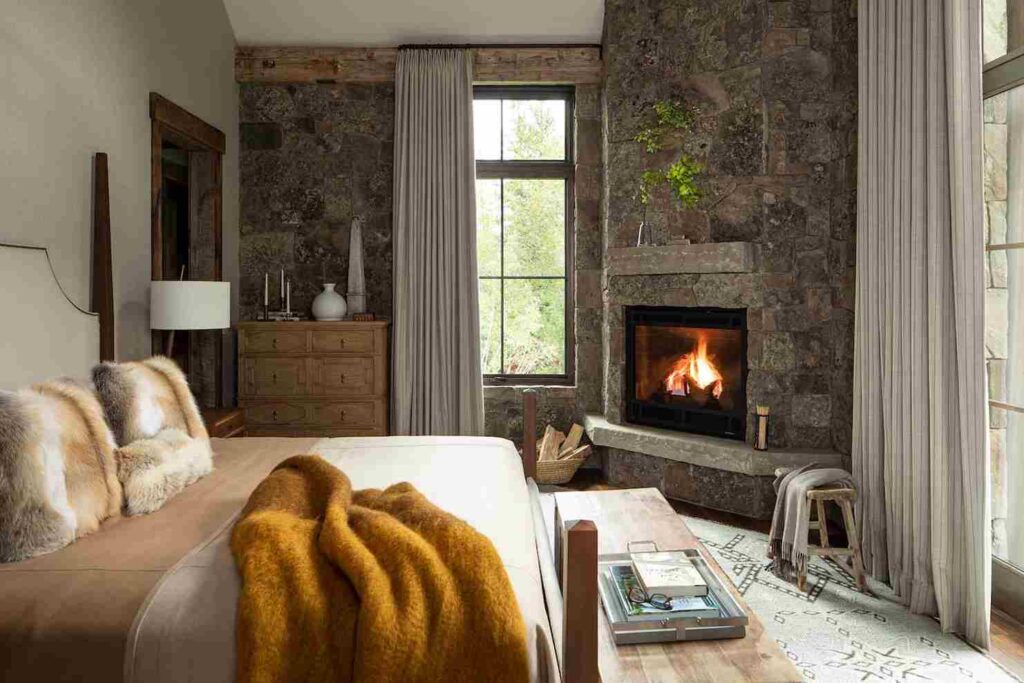 A bedroom with stone wall and fireplace and wooden floor 
