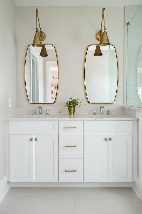 A white vanity with brass fixture and mirror on the wall