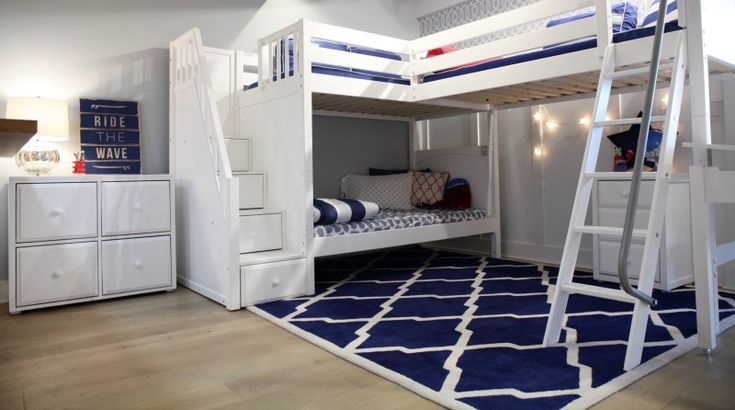 A white loft bed with blue accents and wooden floor and rug on it 