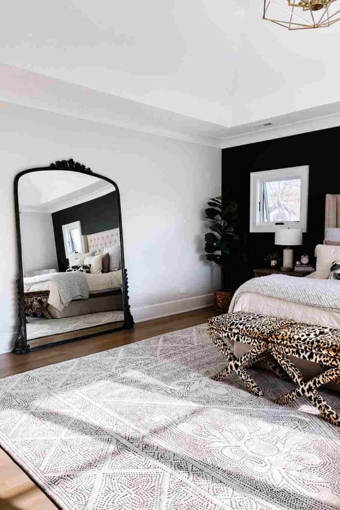 A black bedroom with black framed mirror and rug on the floor 