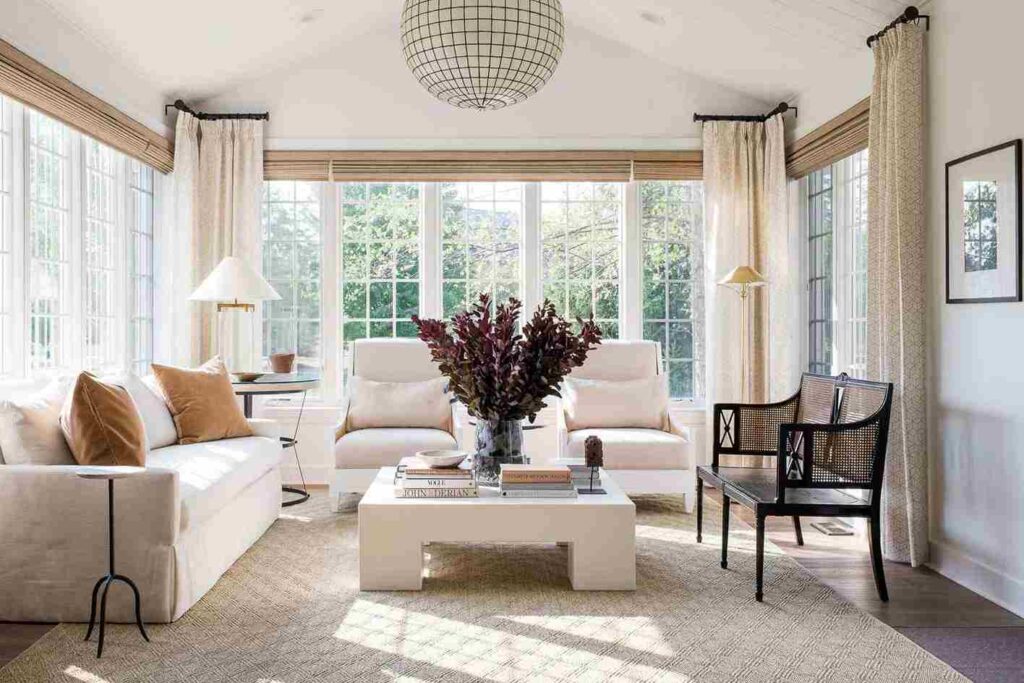 A sunroom with windows curtain and sofa and table and wooden floor 