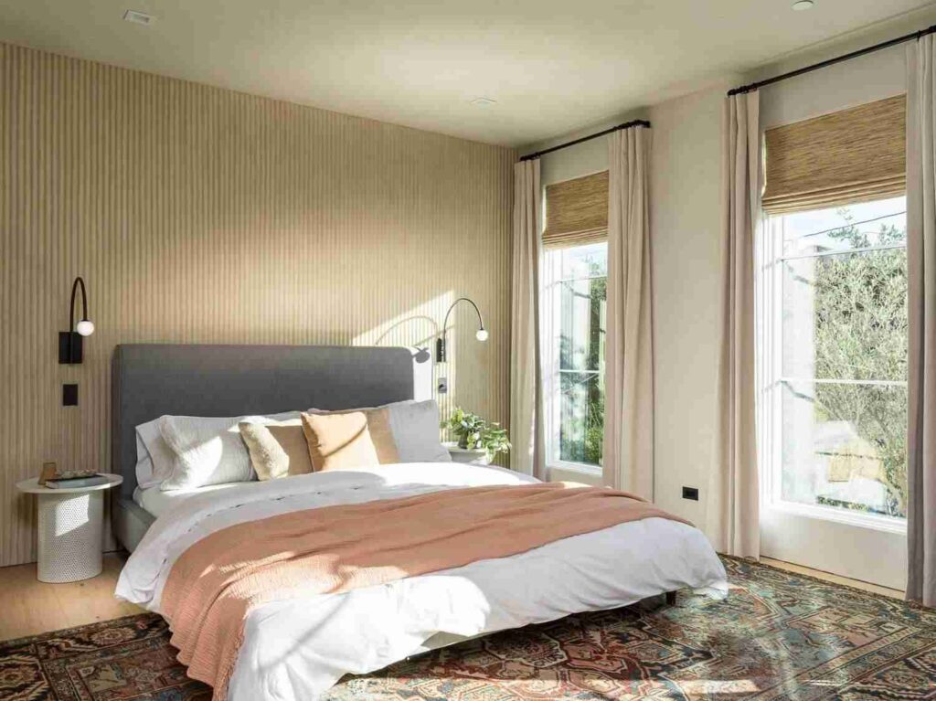 A bedroom with windows treatment and light fixture on the wall 
