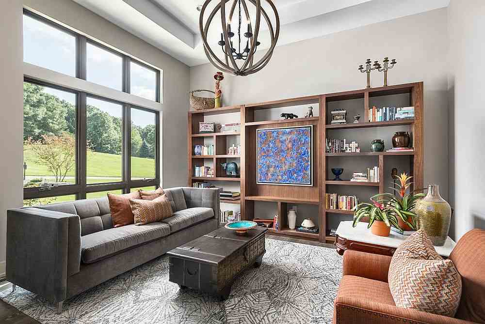 A living room with wooden bookshelves with windows and sofa with table ad rug on the floor 