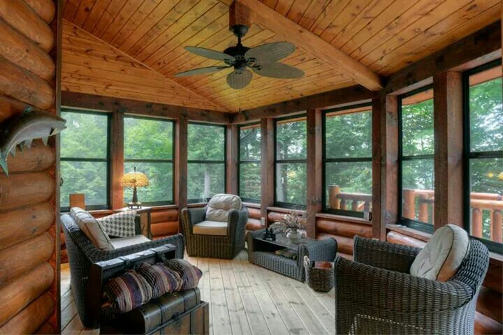 A sunroom with wooden floor and wooden beams celling and sofa and glass windows 