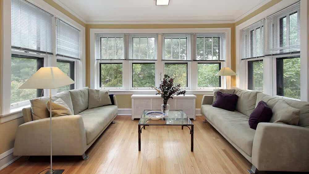 A sunroom with wooden floor and sofa with glass table 