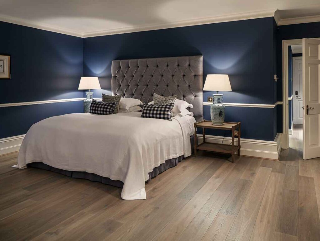 A navy blue bedroom with wooden floor and lamp on the wooden table 
