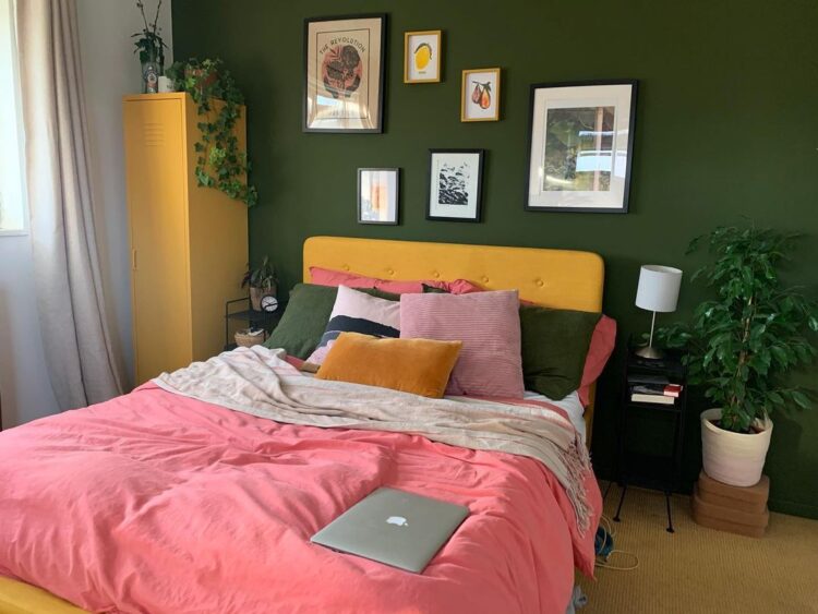 A green bedroom with yellow accents and frames on the wall 
